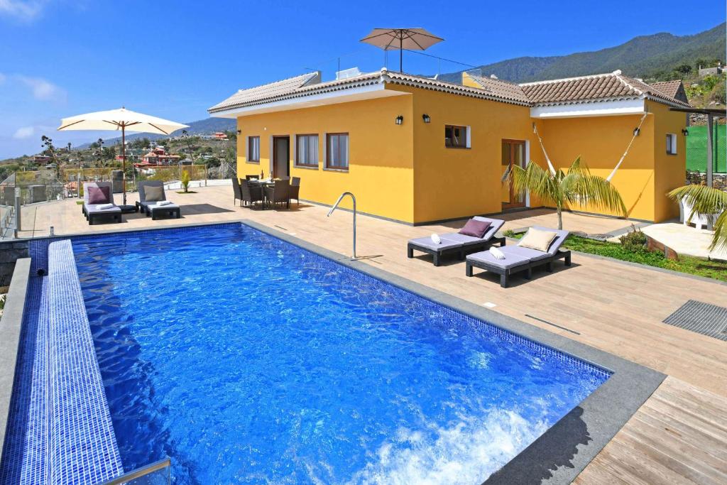 a villa with a swimming pool in front of a house at Villa Mica in Tijarafe