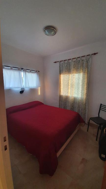 a bedroom with a red bed and two windows at Cabañas Atardecer en Victoria in Victoria