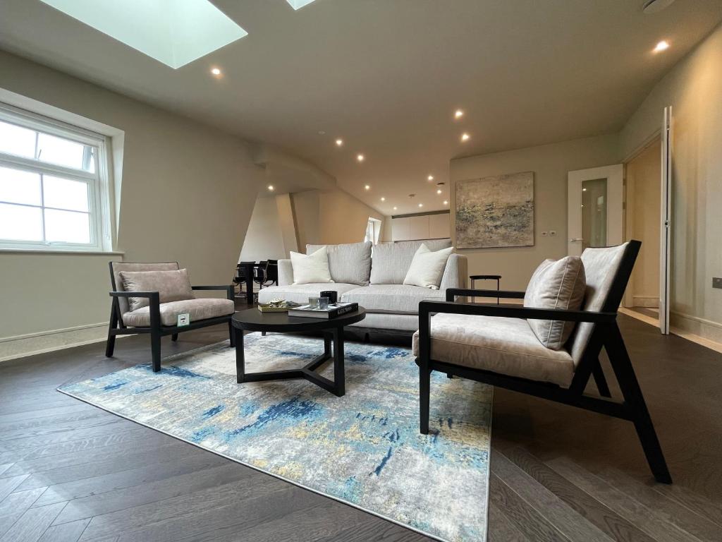 ein Wohnzimmer mit einem Sofa, Stühlen und einem Tisch in der Unterkunft luxurious, 2 bed, 2 bath penthouse apartment in highly desirable Chigwell CHCL F8 in Chigwell
