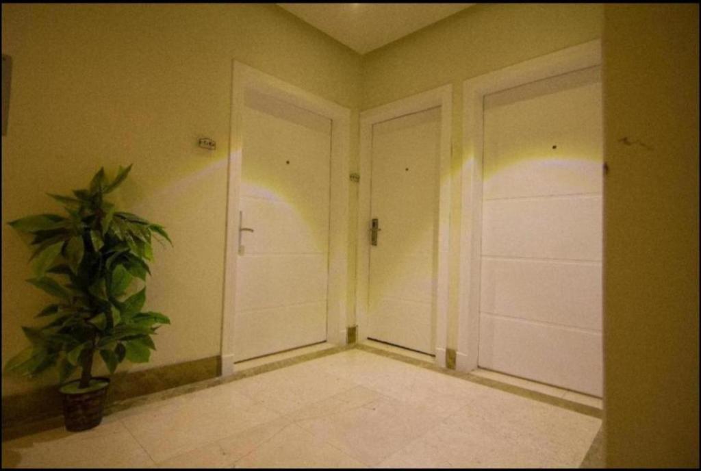 um corredor com duas portas brancas e um vaso de plantas em Reef 18 by Al Azmy em Riyadh