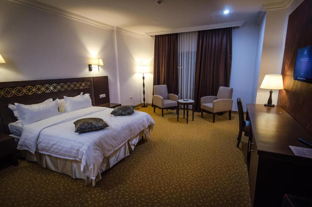 ein Hotelzimmer mit einem großen Bett und zwei Stühlen in der Unterkunft Hotel El Bey in Constantine