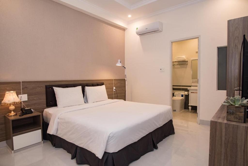 a bedroom with a large white bed and a bathroom at Amora Hotel & Apartment in Vung Tau