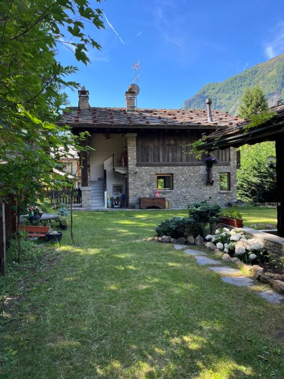 a large stone house with a grass yard at Chalet Blanc "Coeur Sapin" in Courmayeur