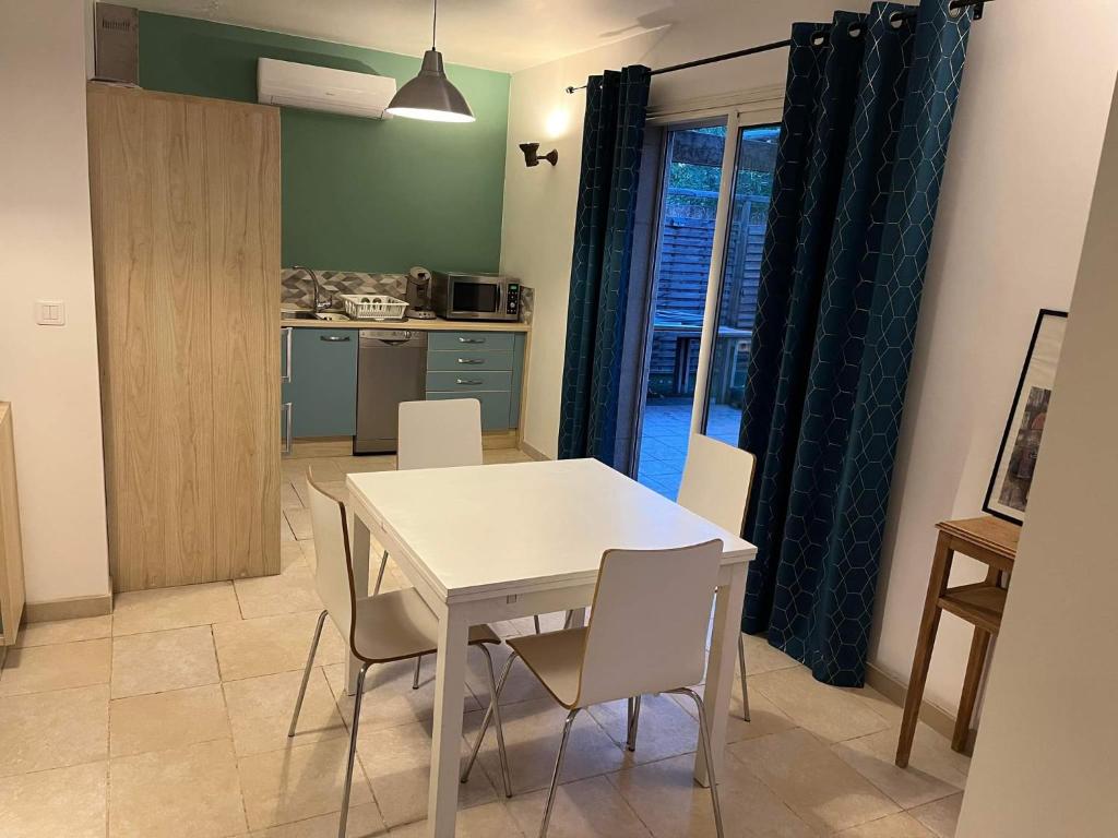 uma cozinha e sala de jantar com uma mesa branca e cadeiras em Cottage Chaleureux tout équipé climatisé à Jacou em Montpellier
