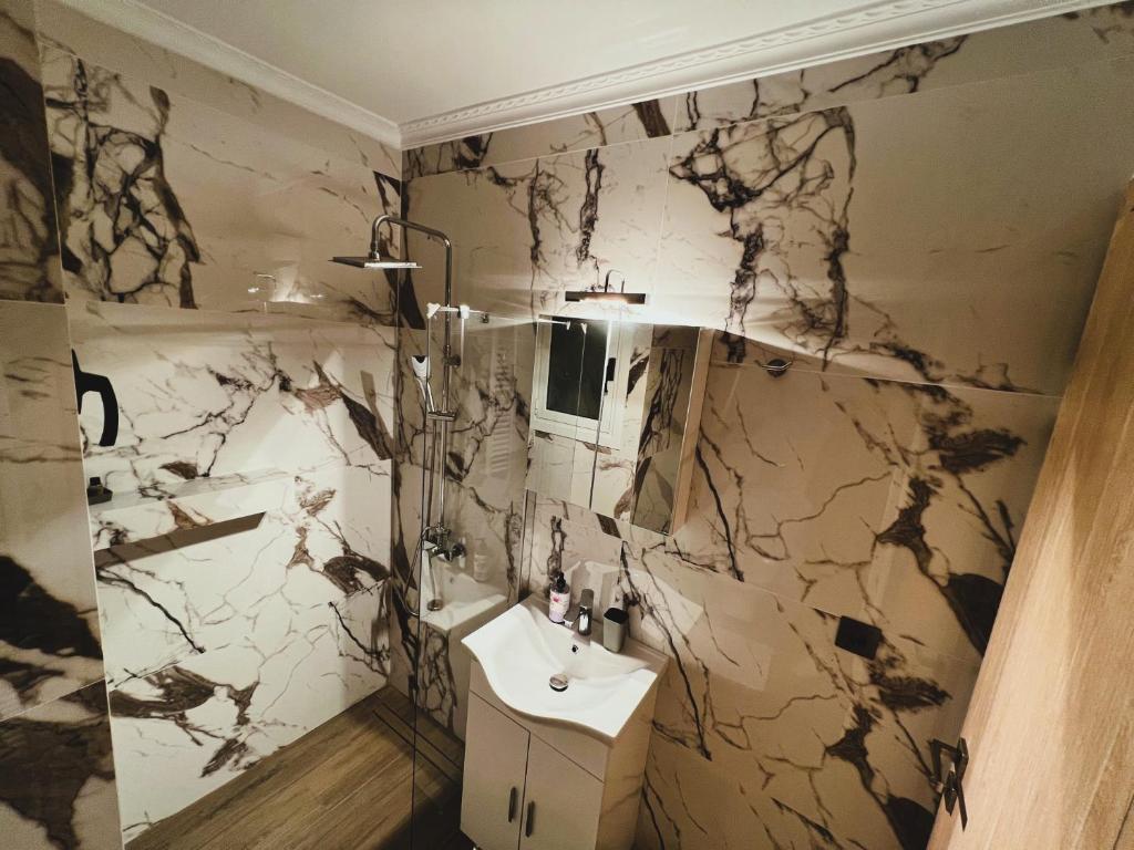 een badkamer met een wastafel en een marmeren muur bij KONTIS' Deluxe furnished apartment in Loutraki