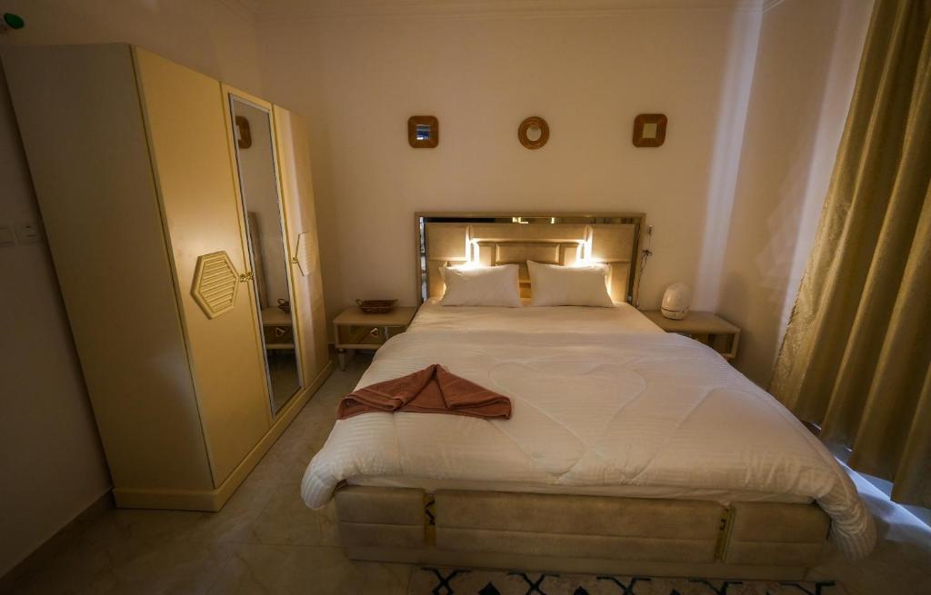 um quarto com uma cama grande e lençóis brancos em نسائم صلاله NassayemSalalah em Salalah