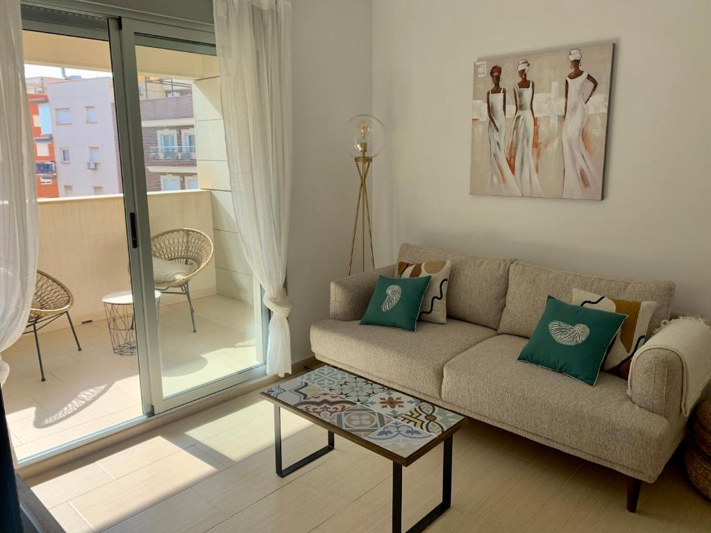 ein Wohnzimmer mit einem Sofa und einem Tisch in der Unterkunft Precioso apartamento primera línea de playa in Águilas