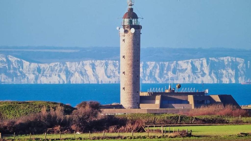 a lighthouse sitting on top of a hill next to the water at Angèle in Audinghen