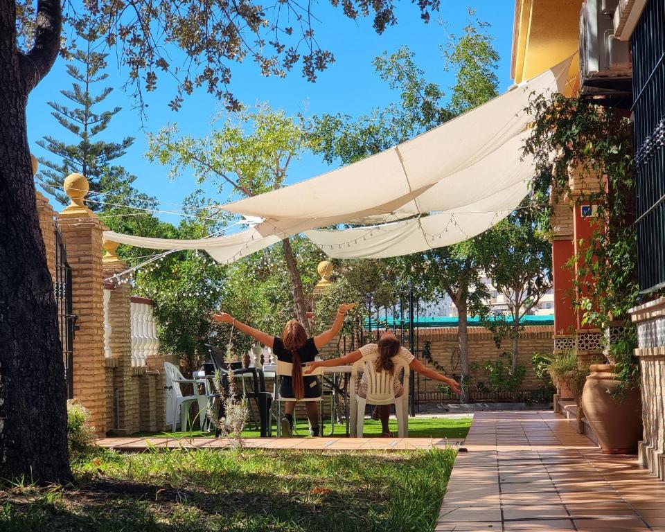 dos personas sentadas bajo un paraguas blanco en un patio en Victoria Hotel en Matalascañas