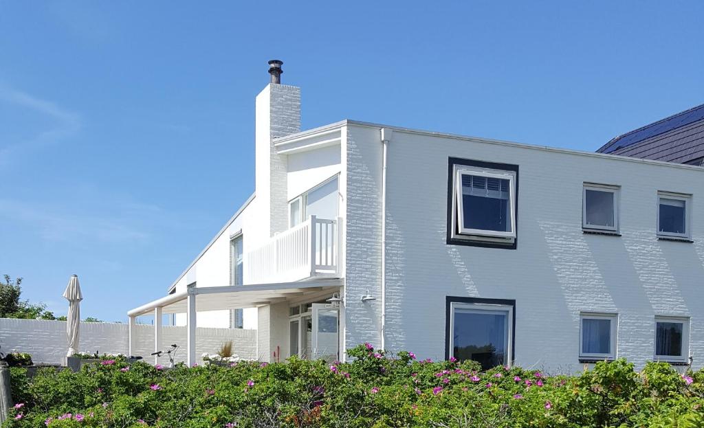 Una casa blanca con una chimenea a un lado. en appartement Ideaal, en Bergen aan Zee
