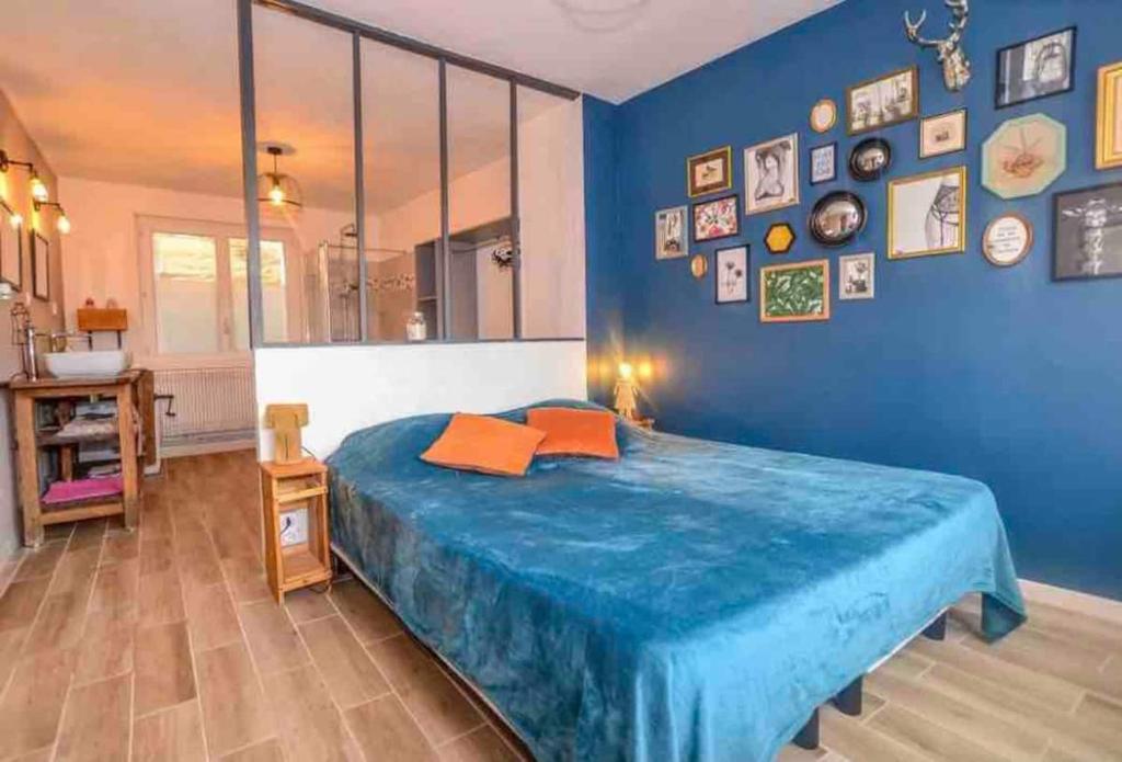 a blue bedroom with a bed and a blue wall at Les Valéricaines in Saint-Valéry-sur-Somme