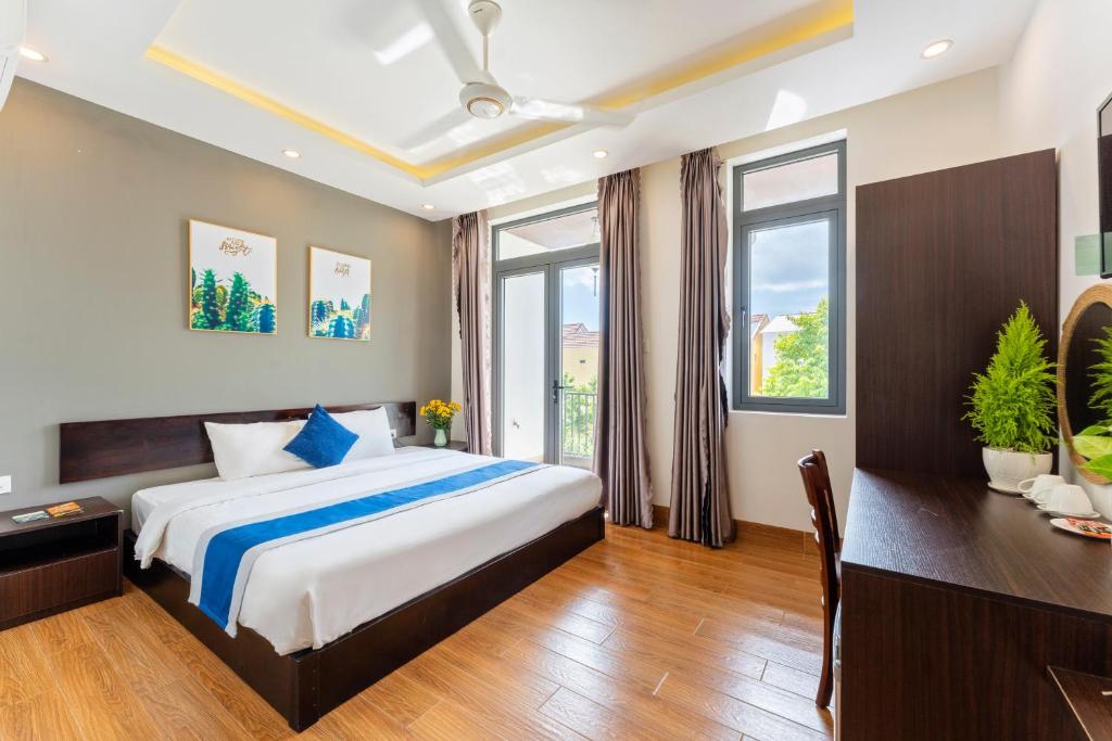 a bedroom with a bed and a desk and windows at Villa Charming Hoi An in Hoi An