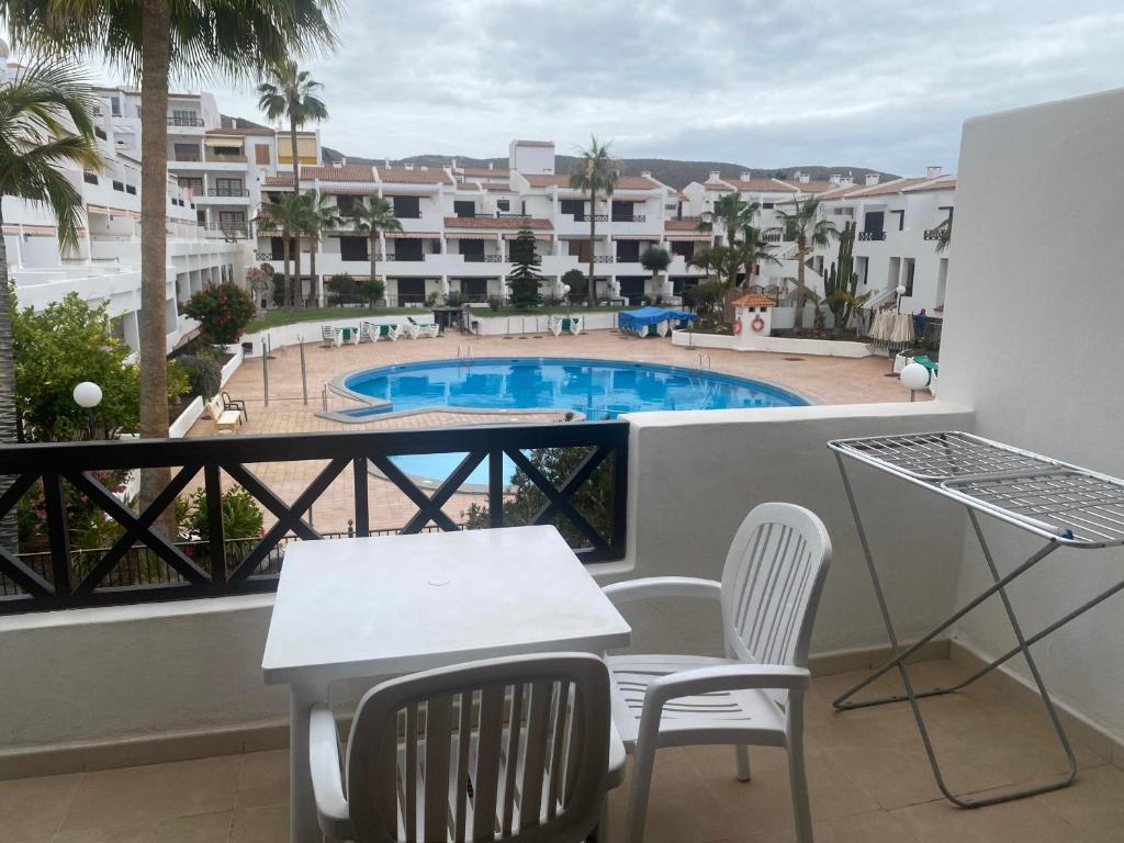 a balcony with a table and chairs and a swimming pool at Apartments Victoria Court 1 6A2 in Arona