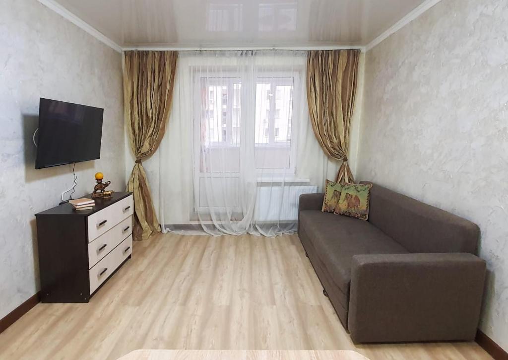 uma sala de estar com um sofá e uma televisão em Уютная квартира в г.Алматы em Almaty
