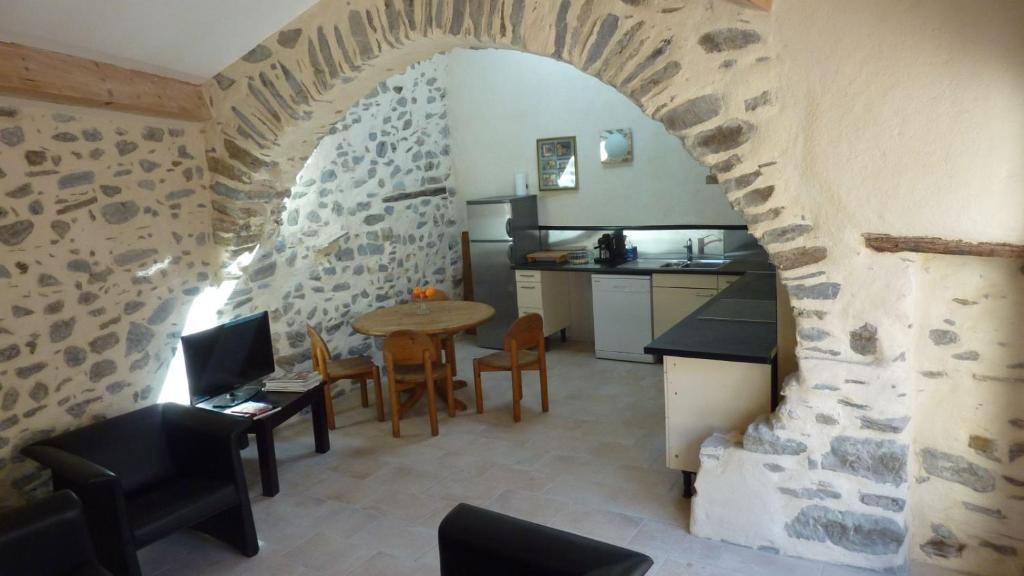 una cucina e una sala da pranzo con parete in pietra di L'Esprit du vallon de Berlou a Berlou