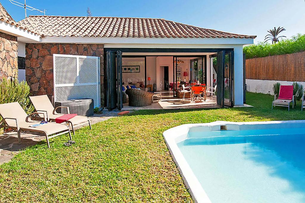 un patio trasero con piscina y una casa en Chalet Isabel en Maspalomas