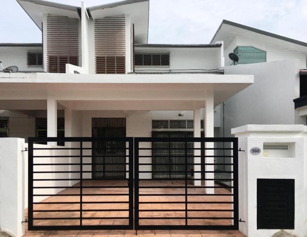 Uma casa branca com um portão à frente. em KUL Rest House em Labu