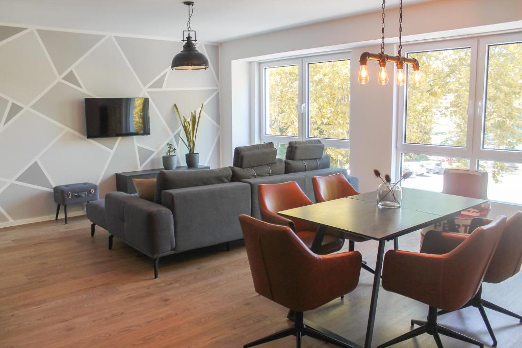 uma sala de estar com um sofá, uma mesa e cadeiras em New York Apartment em Koblenz