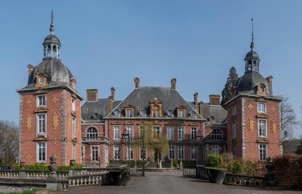 a large red brick building with two turrets at Domaine Du Chateau De La Neuville in Tihange