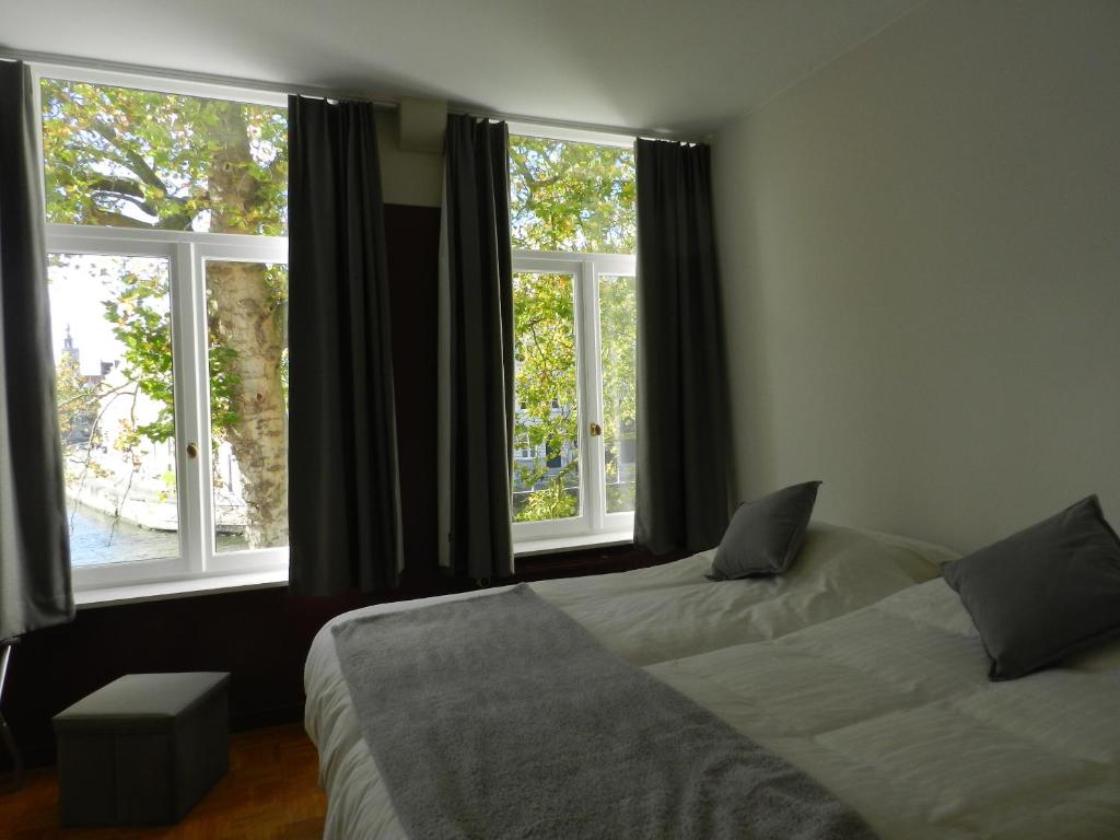two beds in a room with two windows at Apartment St-Anna in Bruges