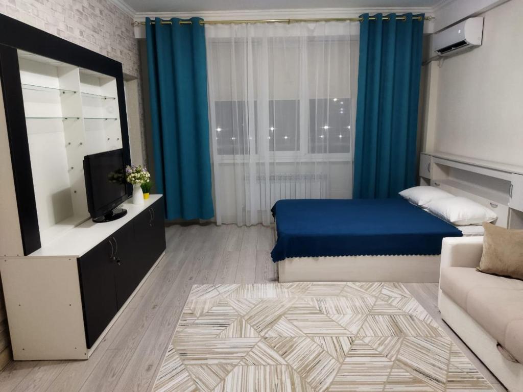 1 dormitorio con 1 cama, TV y sofá en City House, en Aktau