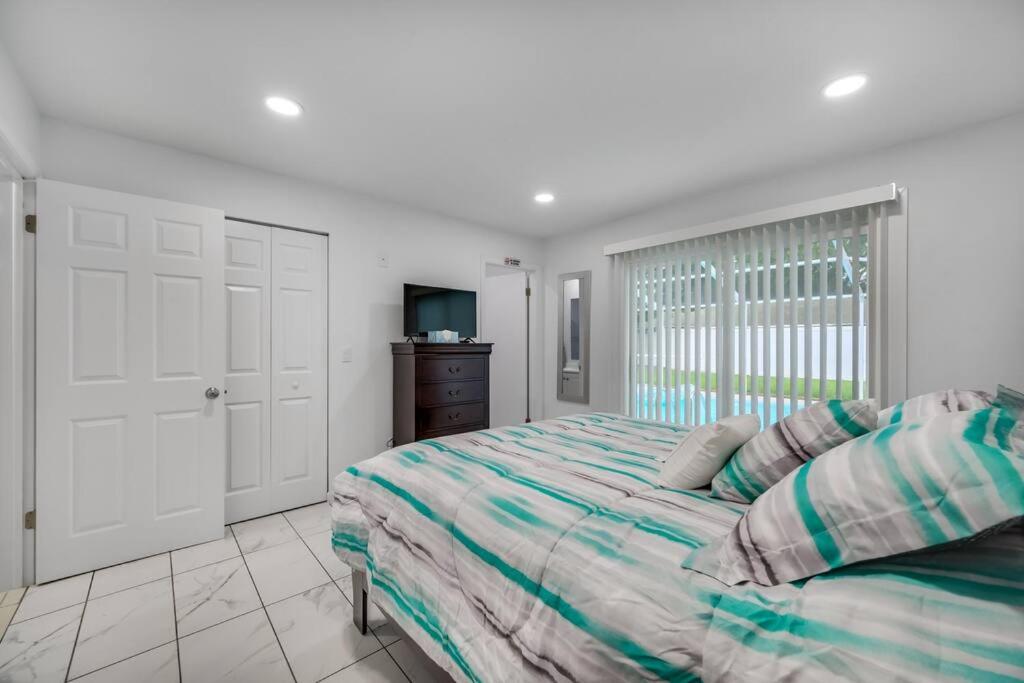 ein weißes Schlafzimmer mit einem Bett und einem TV in der Unterkunft Cozy Family Home in Tampa with Private & Heated POOL, Pool table and Kids Play Area in Tampa