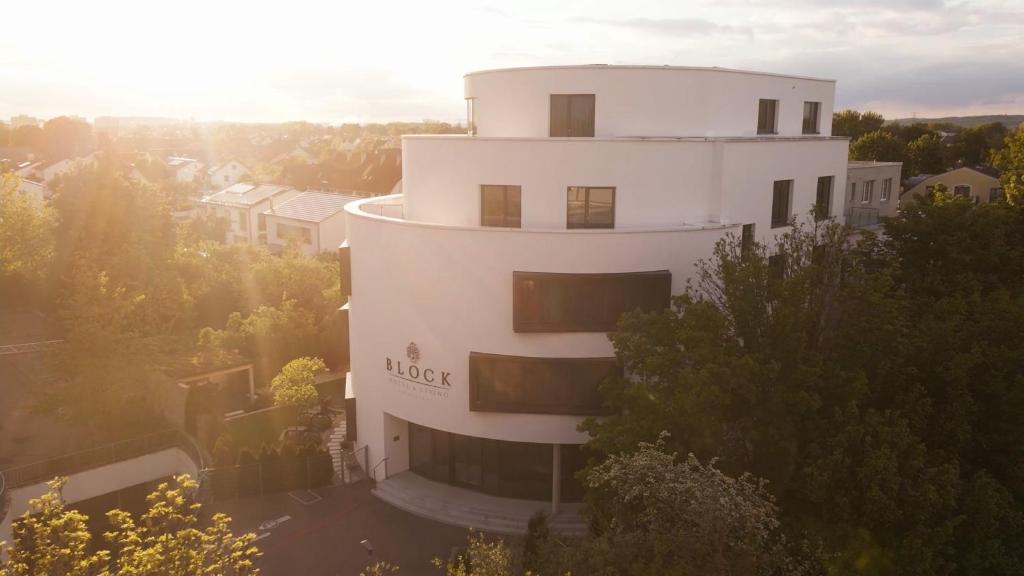 un edificio blanco alto con el sol en el fondo en BLOCK Hotel & Living en Ingolstadt