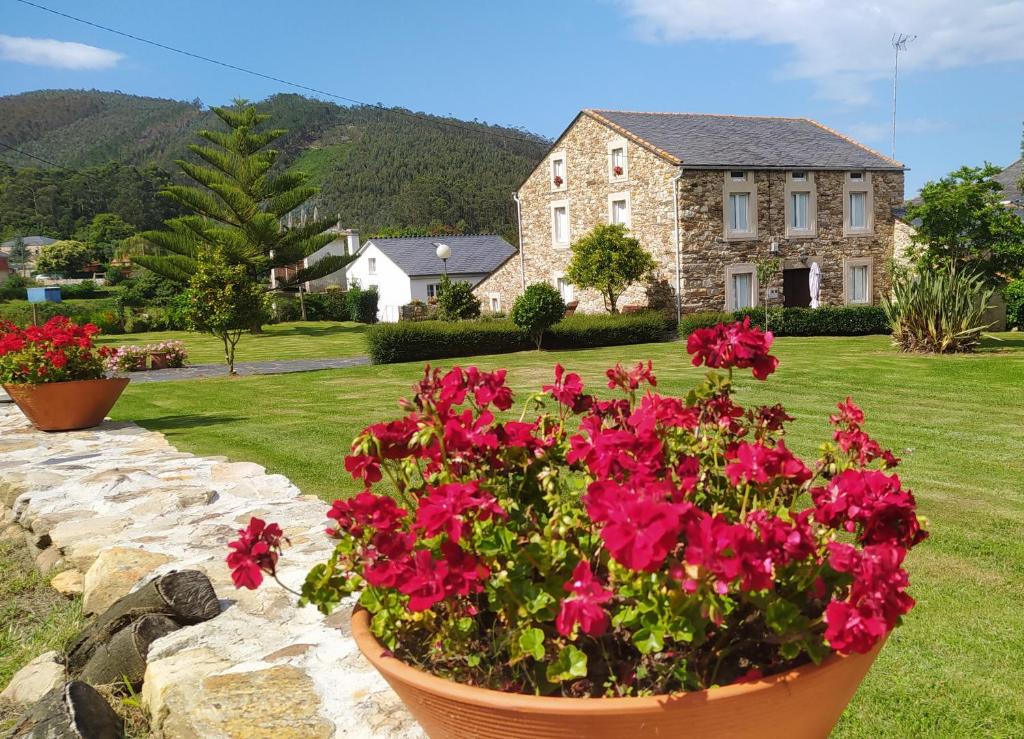 une maison avec des fleurs rouges dans une cour dans l'établissement Casa Valle, à Foz