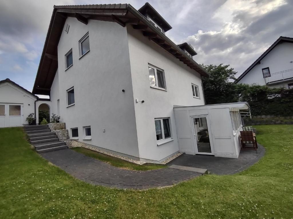 a large white house with a door in a yard at Ferienwohnung Orchidee Eckenhagen in Reichshof 