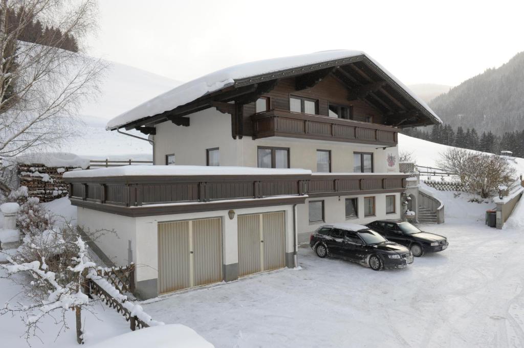 una casa con dos coches aparcados en la nieve en Landhaus Buchsteiner, en Forstau