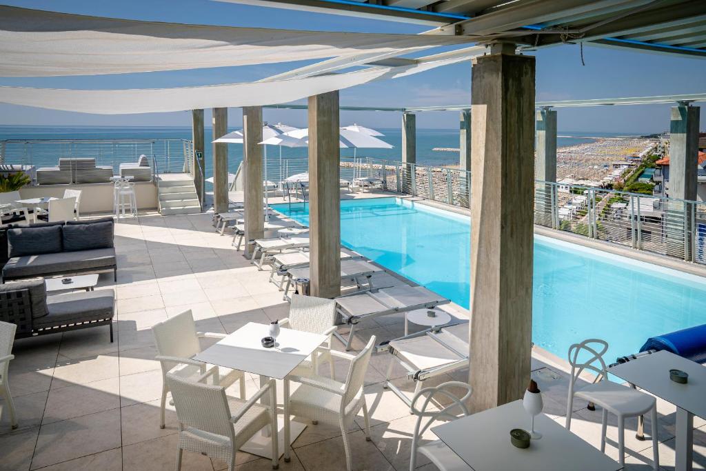 een zwembad op de top van een gebouw met tafels en stoelen bij Hotel Marco Polo in Caorle