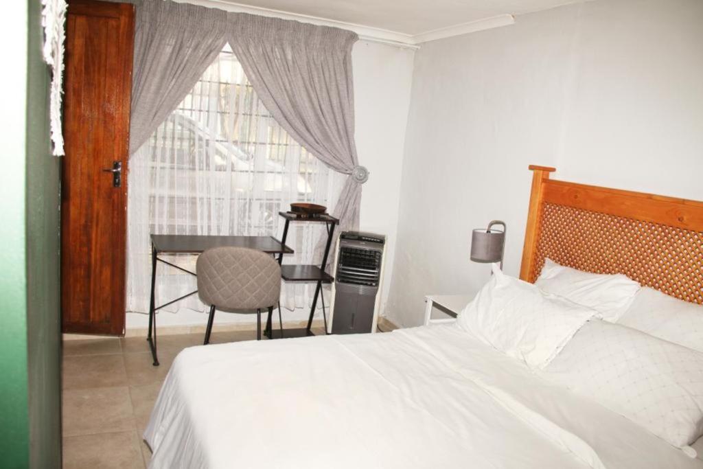 a bedroom with a bed and a table and a window at Adorable 1.5 -Bedroom flatlet in Germiston in Germiston