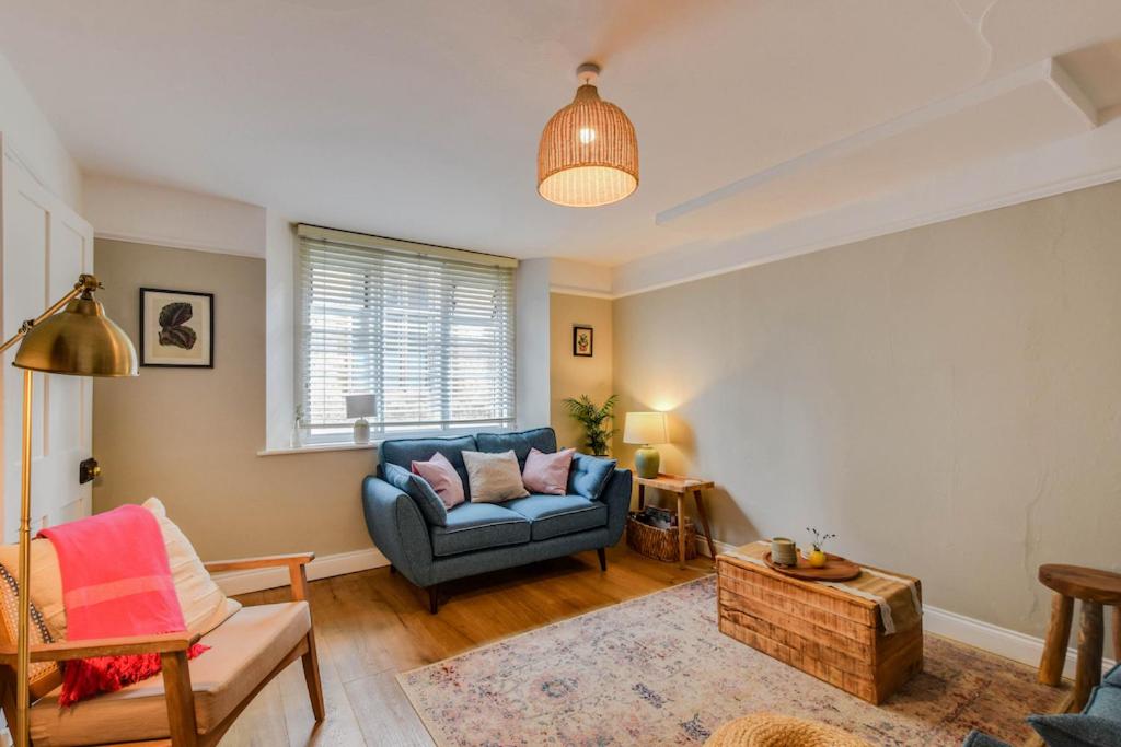 ein Wohnzimmer mit einem blauen Sofa und einem Tisch in der Unterkunft Cheerful 3 bed Grade II Central Cottage in Cirencester