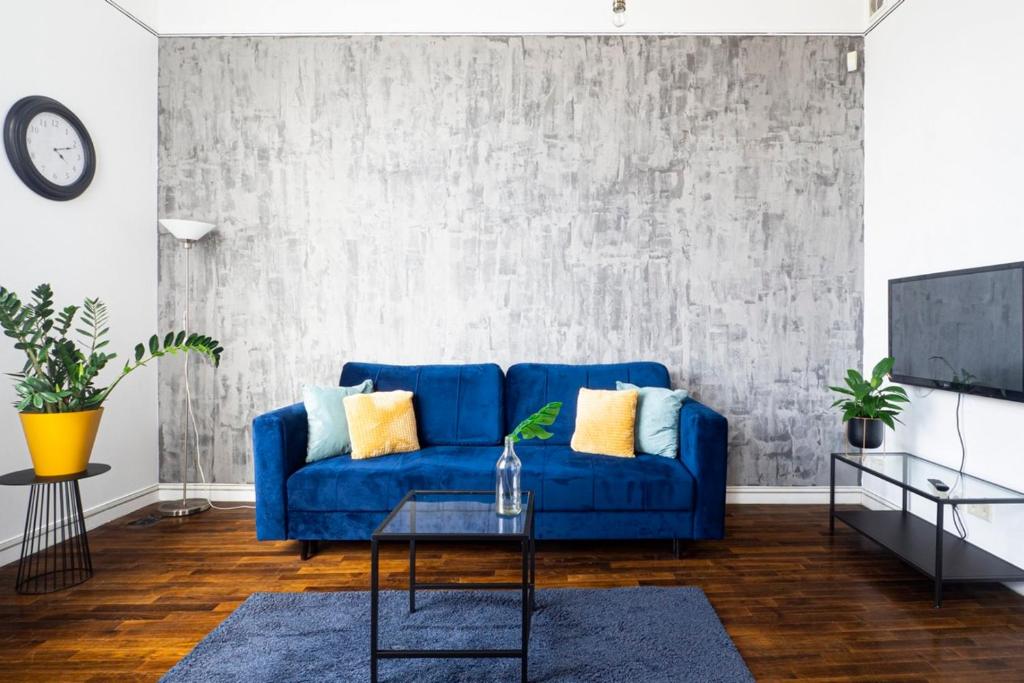 uma sala de estar com um sofá azul e uma televisão em AS HOME Apartamenty Rynek 50 R505 em Breslávia