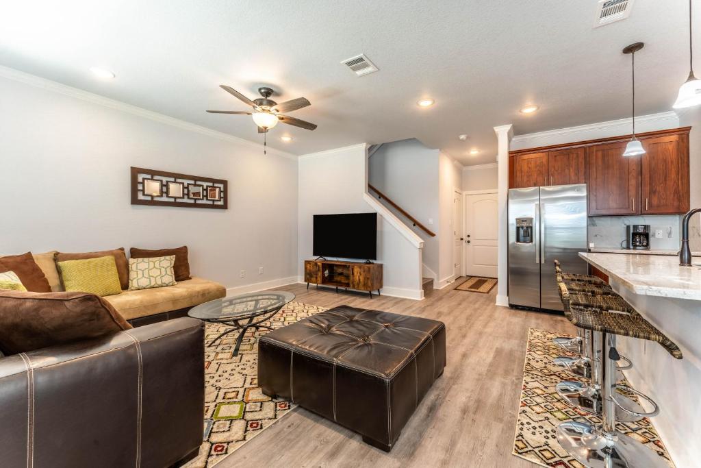 een woonkamer met een bank en een keuken bij Nest - a cheerful 4 bedroom, 4.5 bath new townhome in Aggieland in College Station