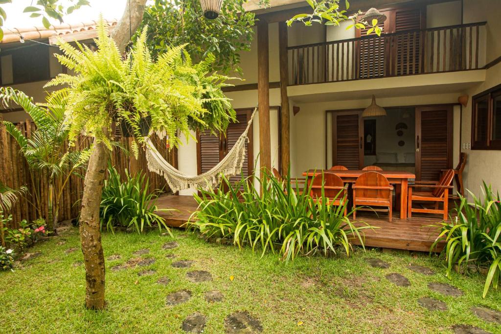 une maison dotée d'une terrasse en bois avec une table et des chaises dans l'établissement Vila Nativa Caraíva, à Caraíva