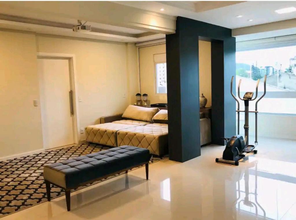 ein Schlafzimmer mit einem Bett und einer Bank in einem Zimmer in der Unterkunft Apartamento Executivo - No melhor lugar do América in Joinville