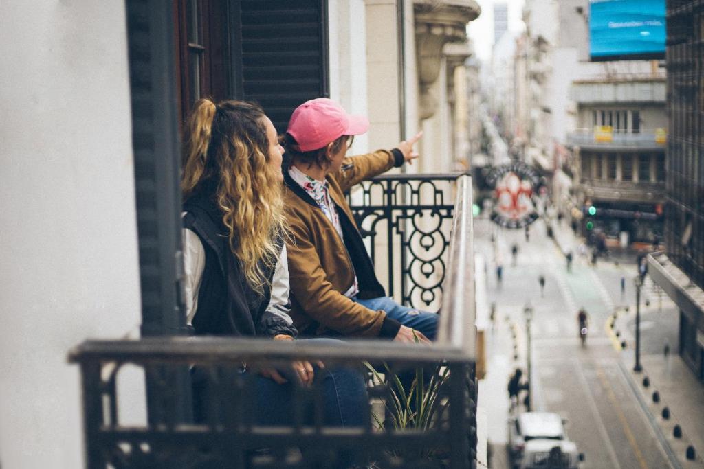 Dos personas sentadas en un balcón con vistas a una ventana en IDEAL SOCIAL Hostel en Buenos Aires