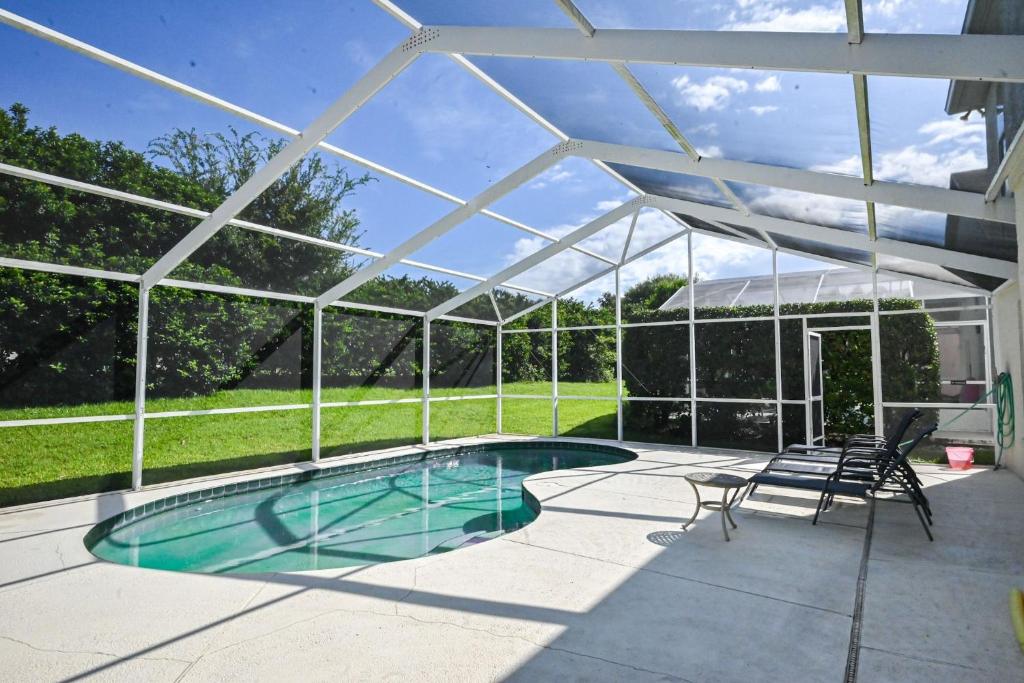 a swimming pool under a pavilion with chairs and a table at Golf getaway fun for family and friends for an Orlando theme park vacation in Davenport