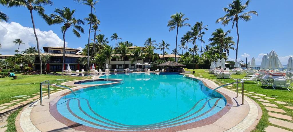 einen Pool in einem Resort mit Palmen in der Unterkunft Praia do Forte - ap Bali Bahia 107 in Praia do Forte