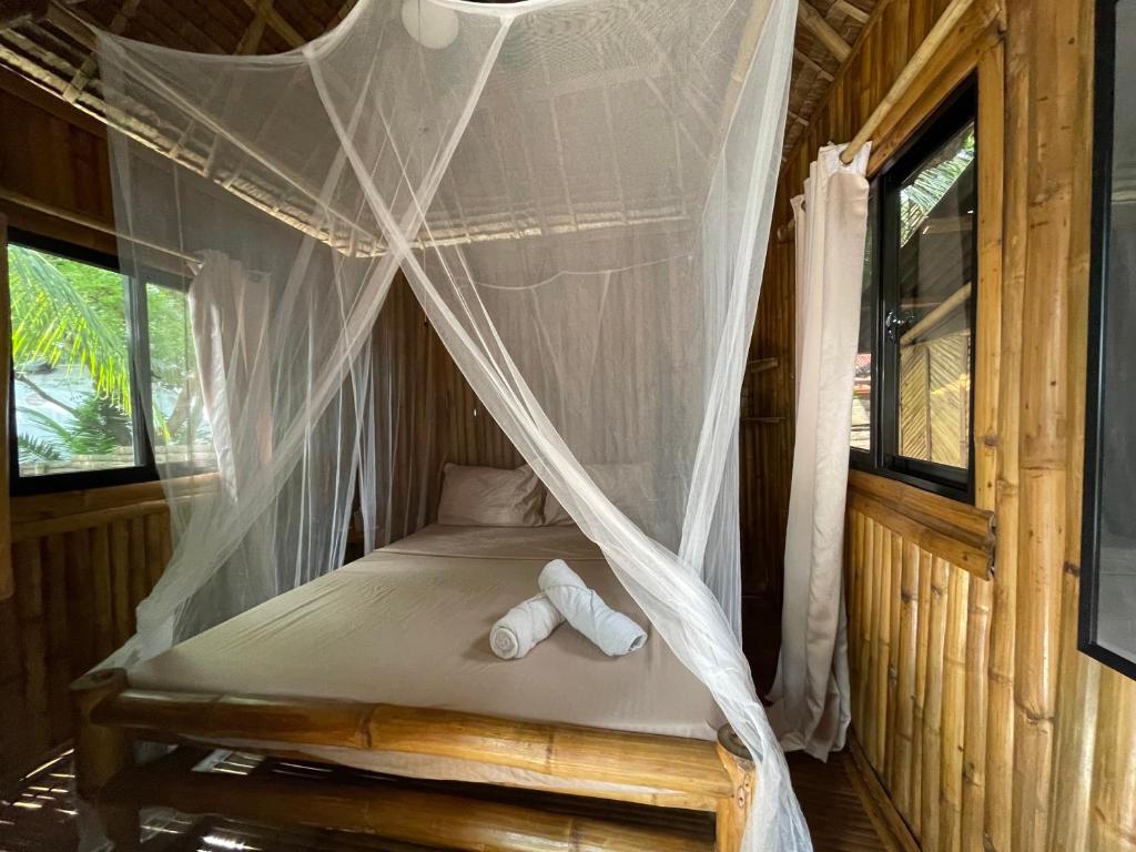 a bed in a room with a mosquito net at La Tortue Diving Resort Dauin in Dauin