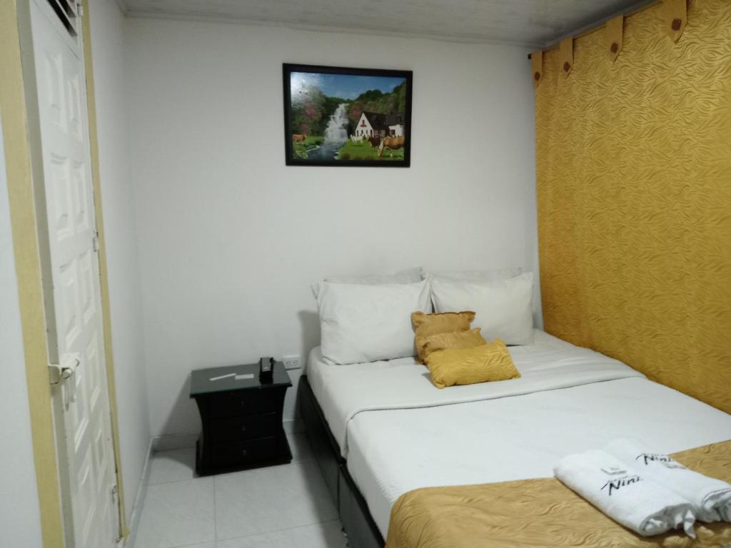 a small bedroom with a white bed with yellow pillows at Hotel Casa Nini in Bogotá