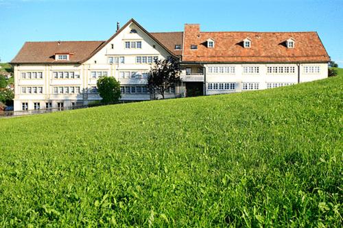 a large white building on top of a green field at Hotel am Schönenbühl in Speicher