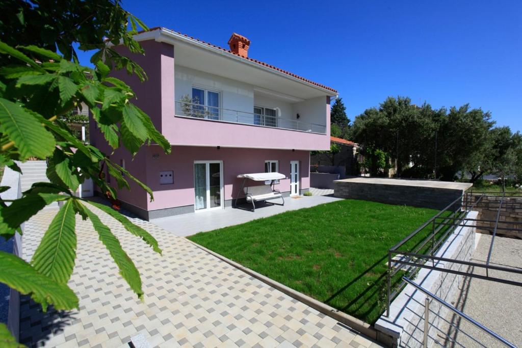una casa rosa con césped delante en Holiday house with a parking space Premantura, Medulin - 11631, en Premantura