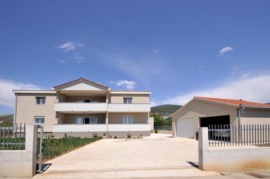 Biały dom z płotem przed nim w obiekcie Apartments with a parking space Plano, Trogir - 11649 w Trogirze