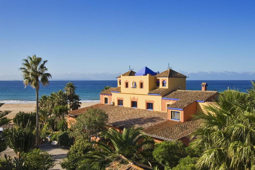 una casa sulla spiaggia con palme di Beach Hotel Dos Mares a Tarifa