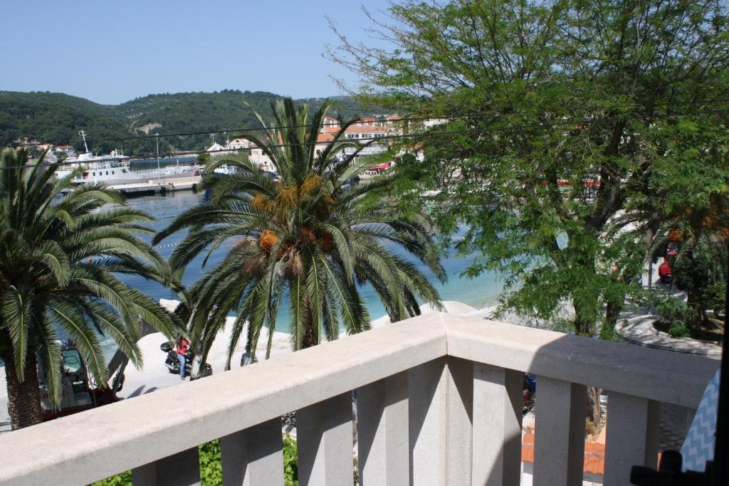 a balcony with palm trees and a body of water at Apartments by the sea Sumartin, Brac - 11651 in Sumartin