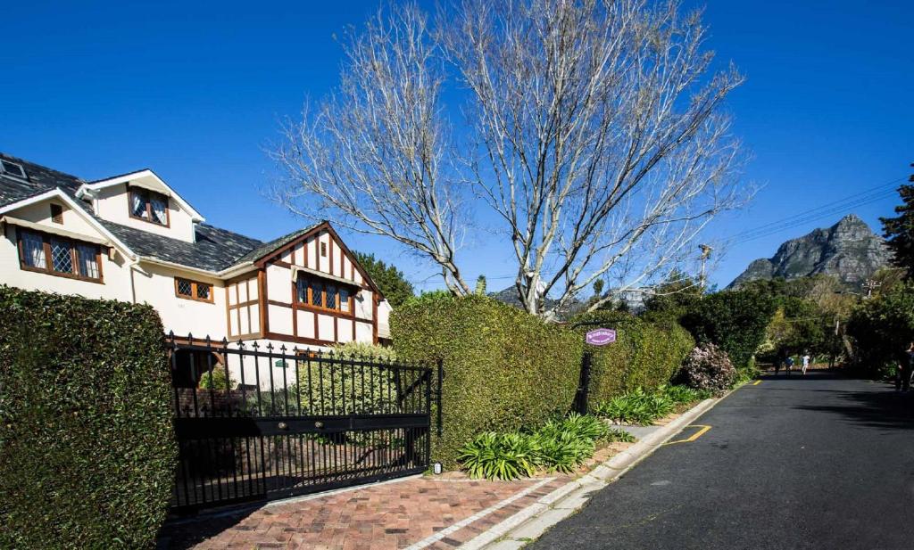 ein weißes Haus mit einem Zaun und einem Baum in der Unterkunft Knightsbury Guest House in Kapstadt