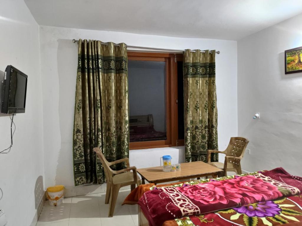 a room with a table and a bed and a window at WonderLand Guest House in Udhampur