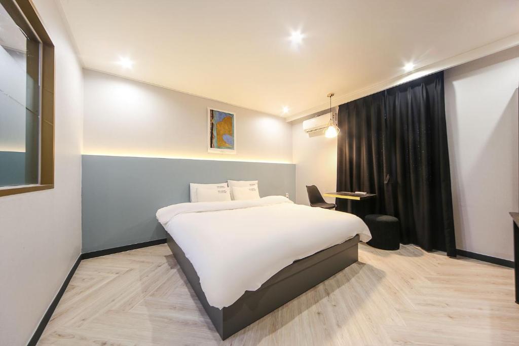 Un dormitorio con una gran cama blanca y una ventana en Masan First Class Hotel en Changwon